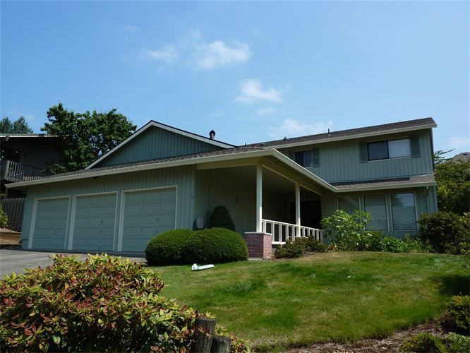 A green house with three garage doors and a porch