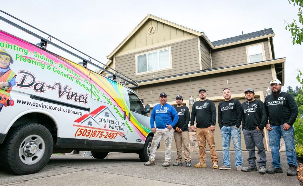 A group of men are standing in front of a house next to a truck.
