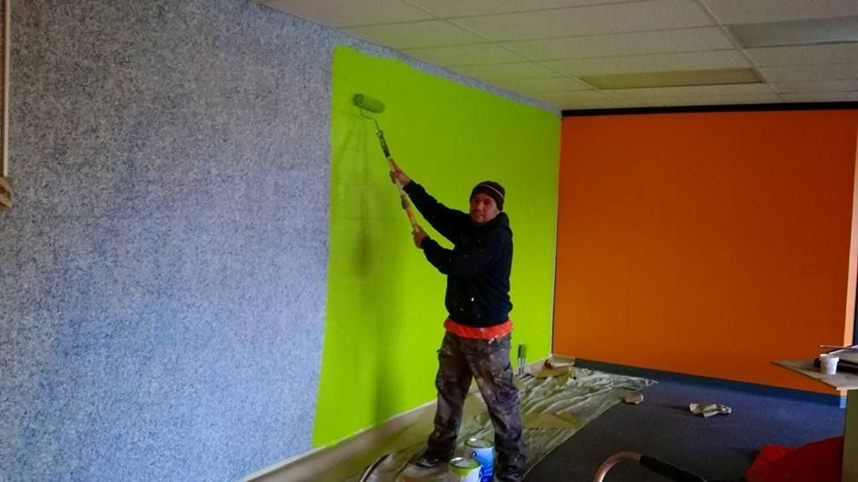 A man is painting a wall with a roller.