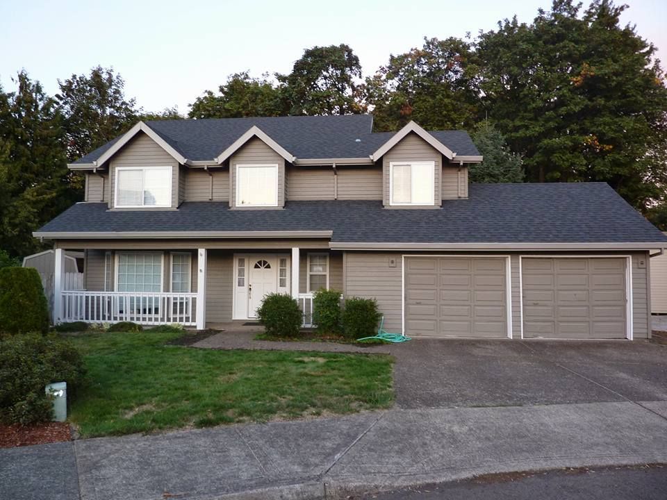 A house with a gray siding and a black roof