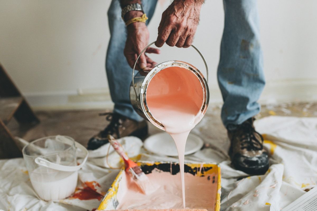 A man is pouring pink paint into a tray.
