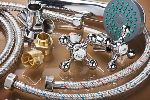 Chrome shower head, faucets, and flexible hoses displayed on a reflective surface.