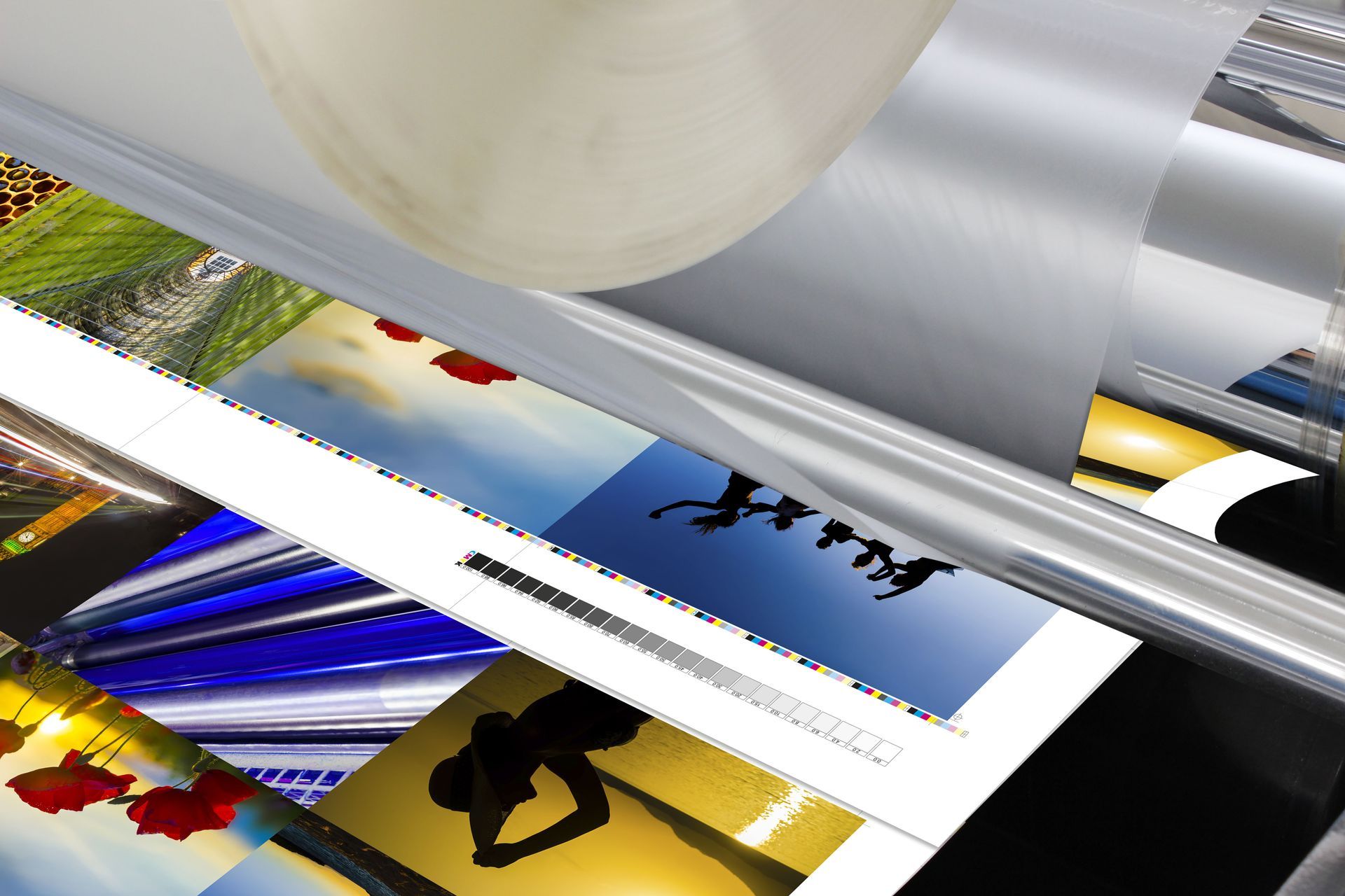 Laminating machine processing colorful printed images, with a roll of clear film on top.