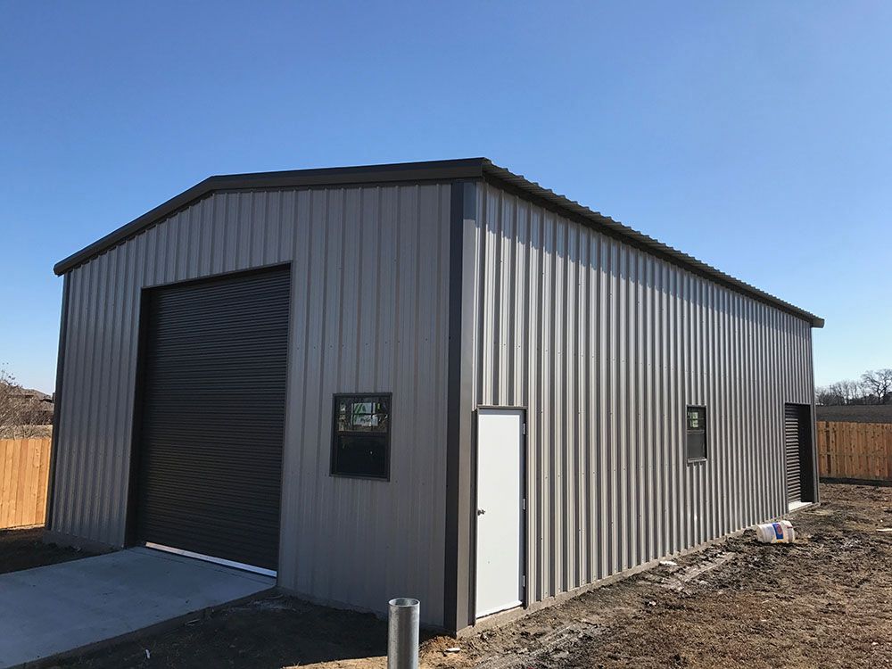 A large metal building with a black garage door and a white door.