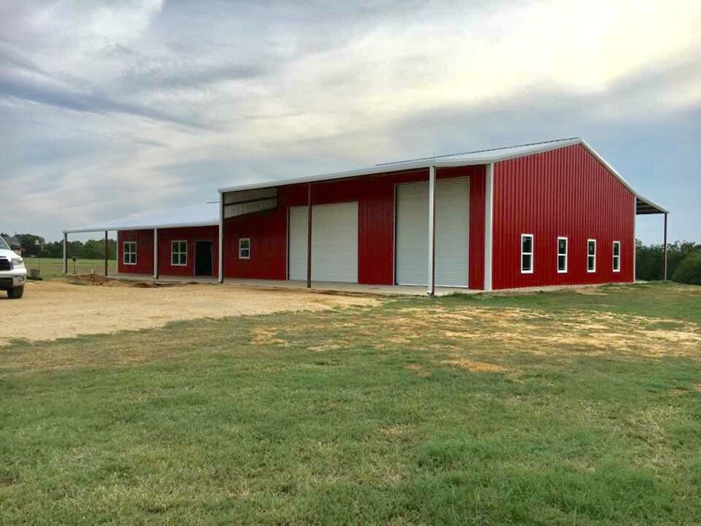 A red barn is sitting in the middle of a grassy field.