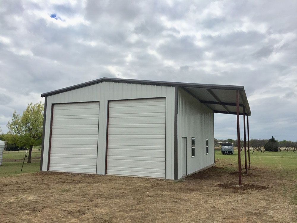A white garage with a carport attached to it in a field.