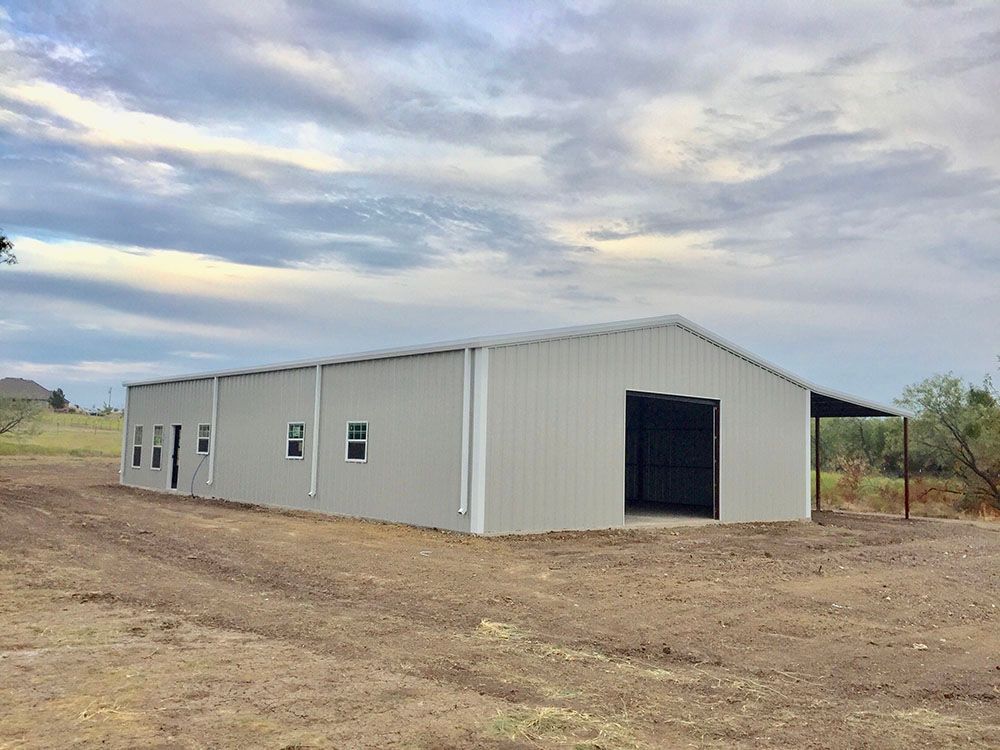 A large white building is sitting in the middle of a dirt field.