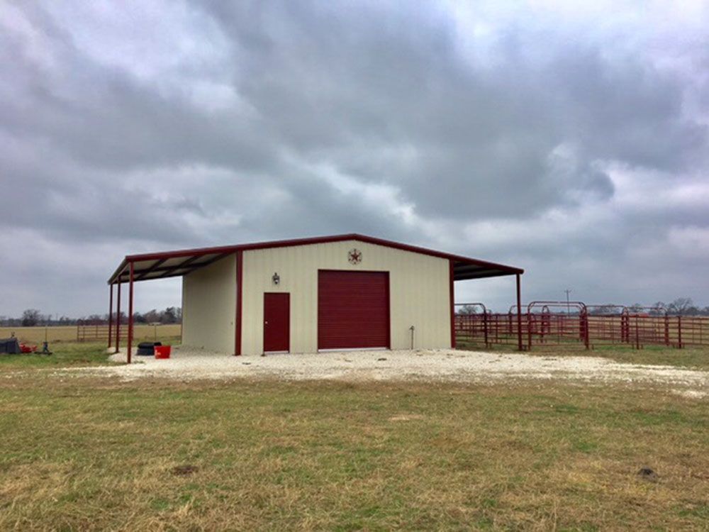 A white building with a red door is in the middle of a grassy field.