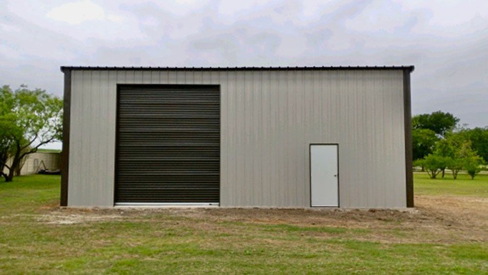 A metal building with a black garage door and a white door.
