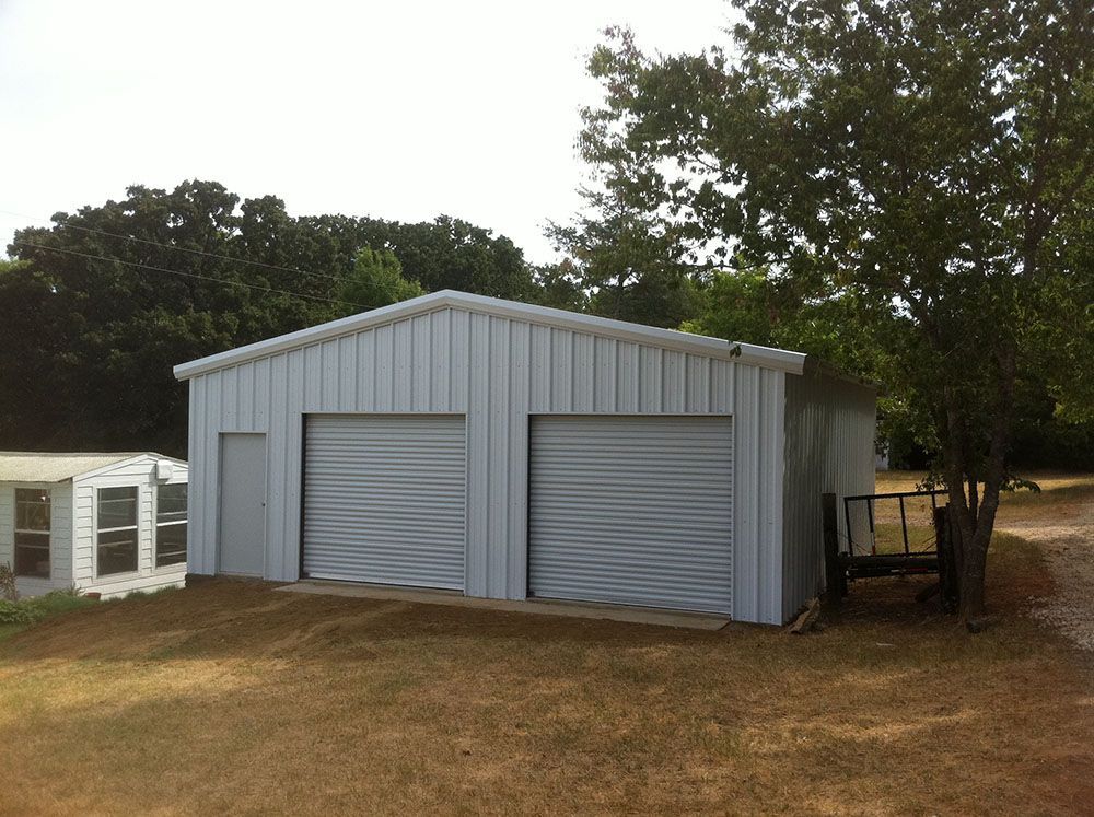 A white garage with two garage doors and a trailer in front of it