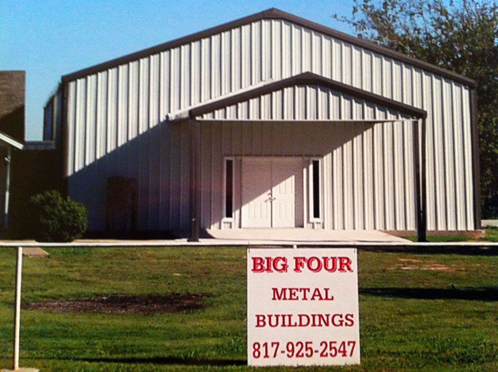 A large metal building with a big four metal buildings sign in front of it