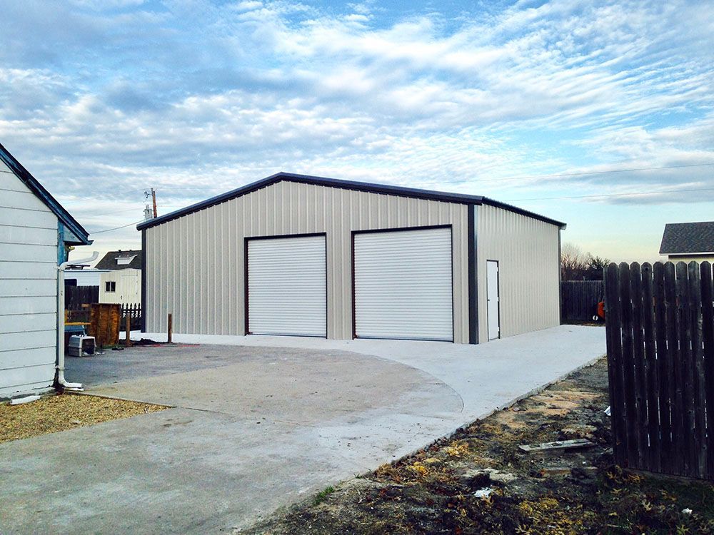 A large metal building with two garage doors and a driveway