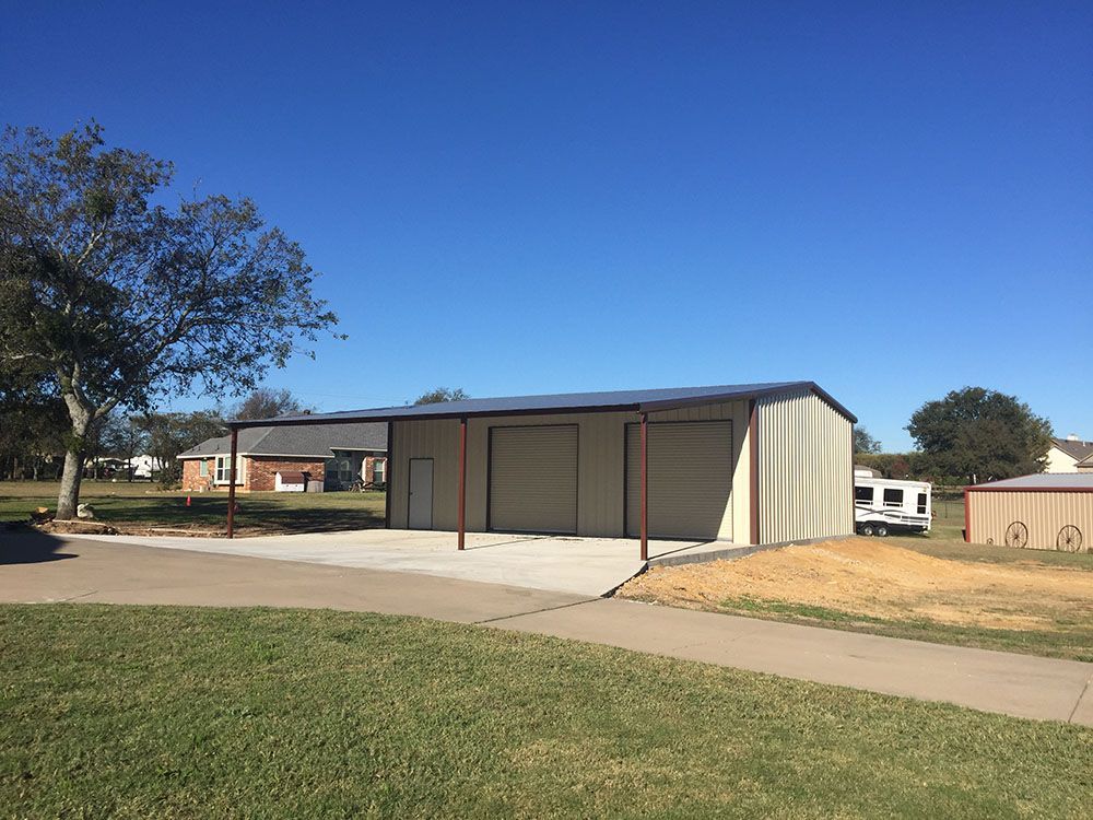 A large metal garage with a driveway in front of it.