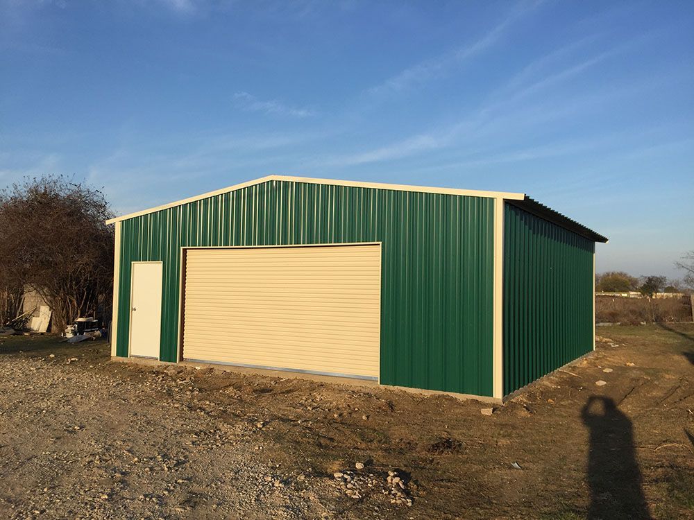 A green and tan metal garage with a garage door.