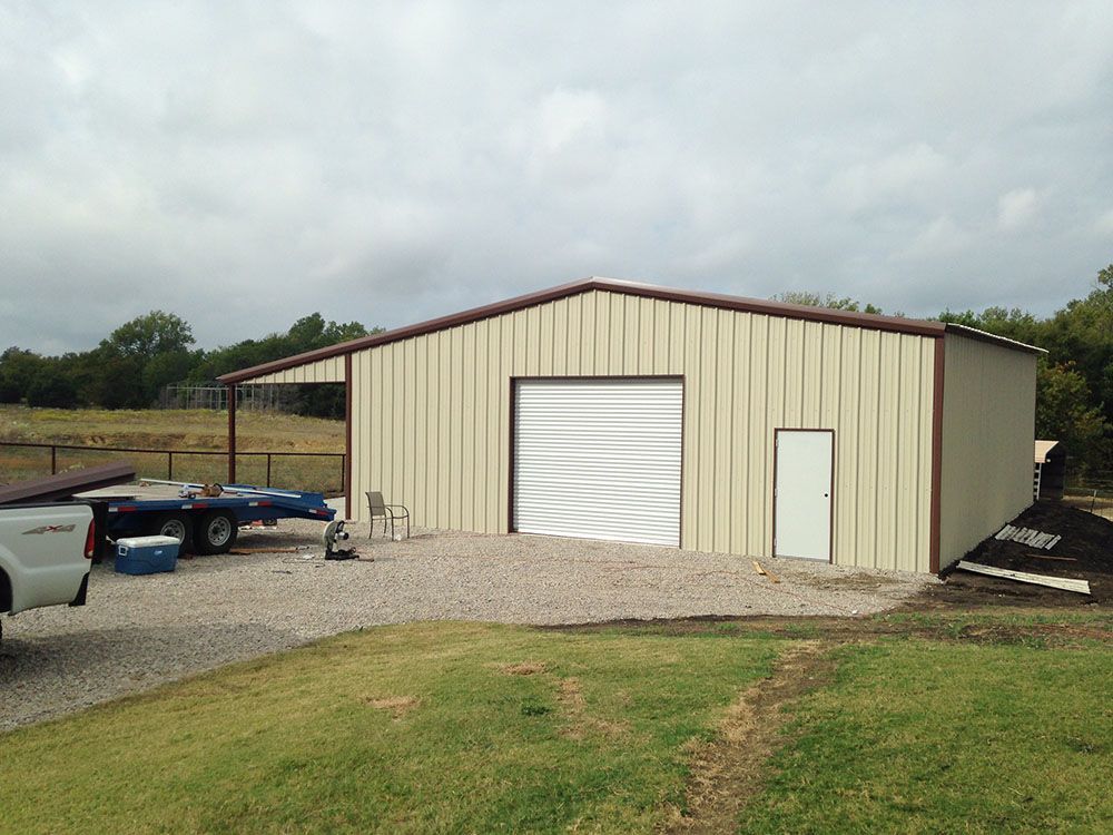 A white truck is parked in front of a large metal building.