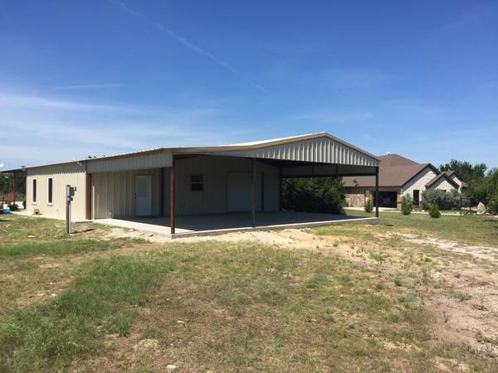 A large metal building with a carport in front of a house.