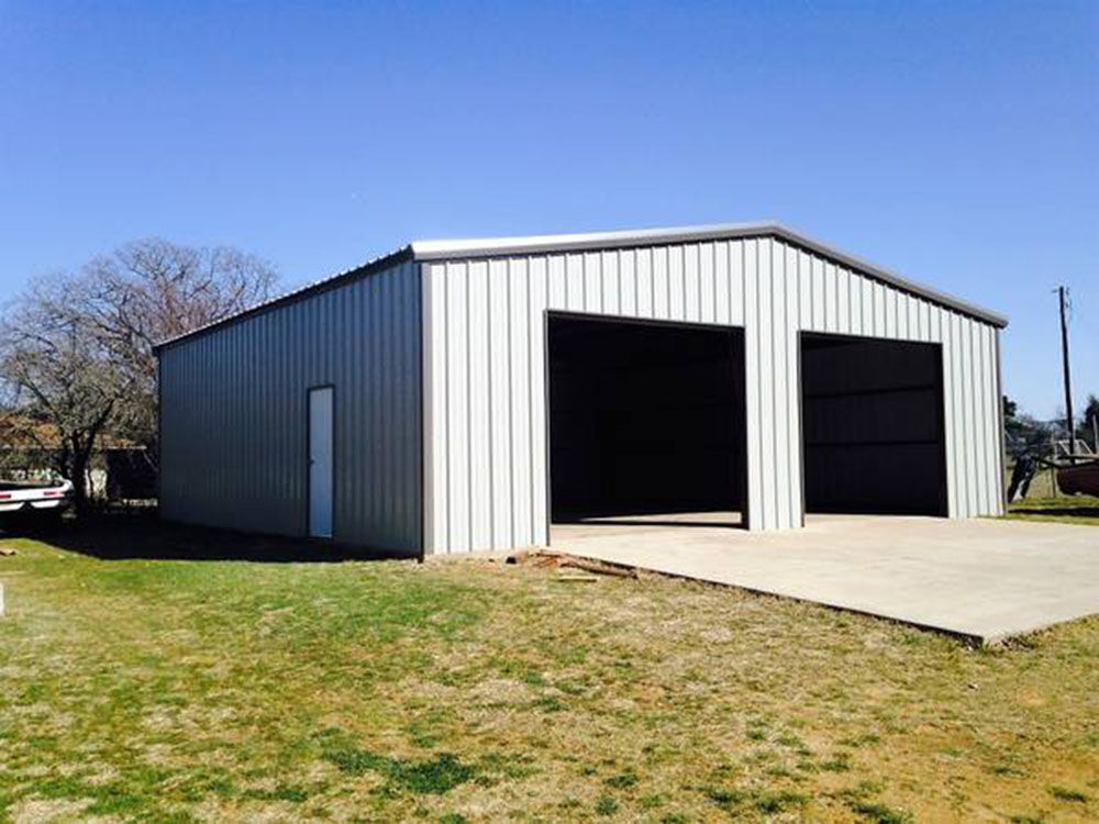 A white metal garage with two doors and a concrete driveway