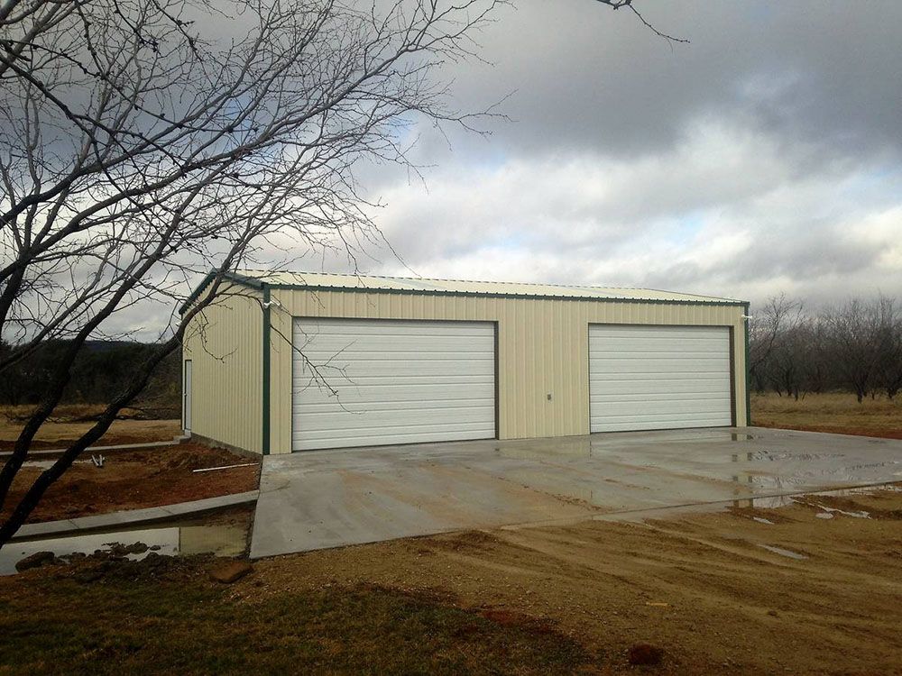 A garage with two white garage doors on a cloudy day
