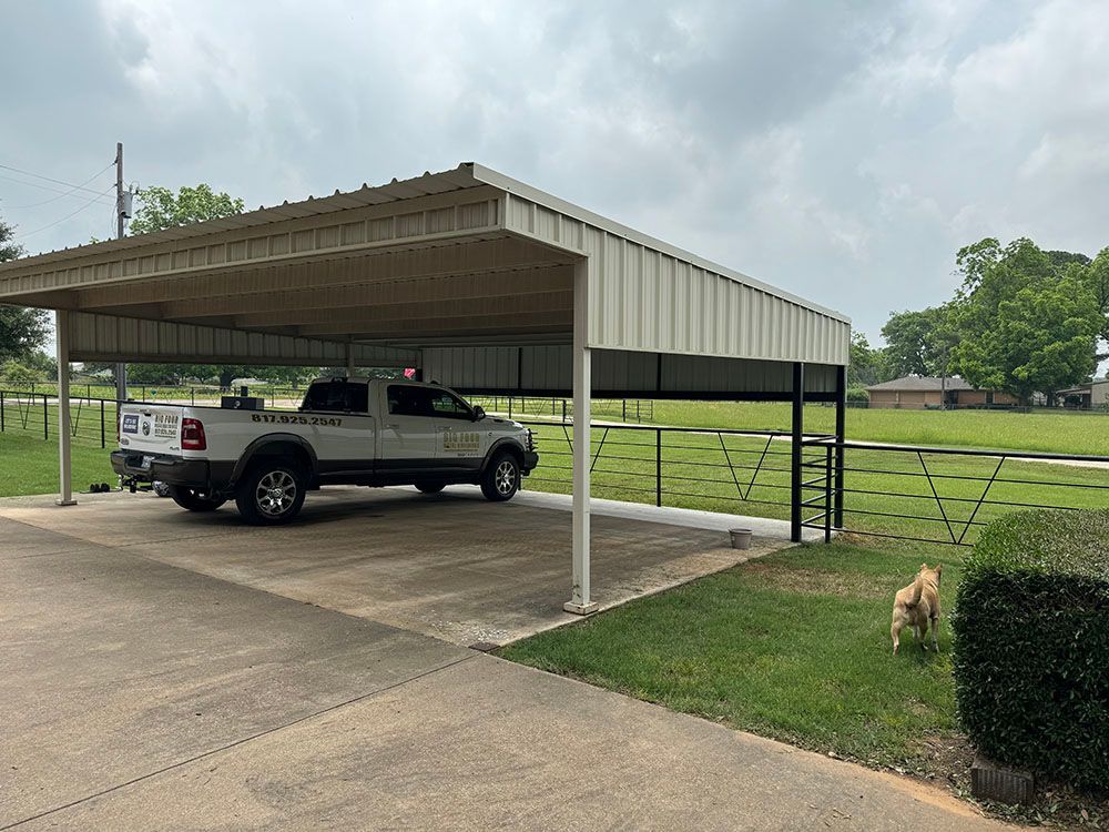 A truck is parked under a carport in a driveway.