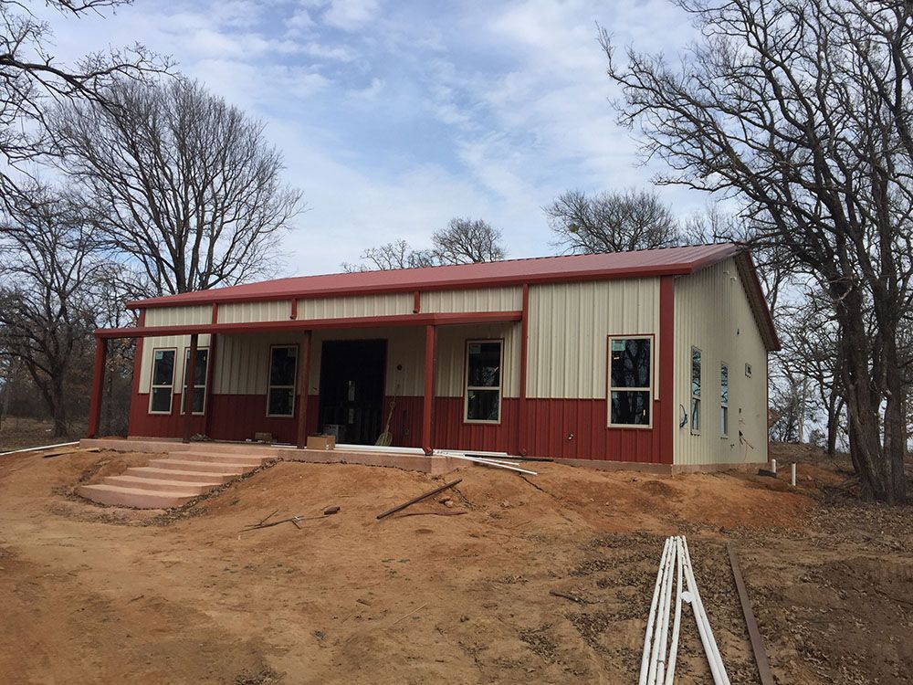 A red and white building with a red roof is sitting in the middle of a dirt field.