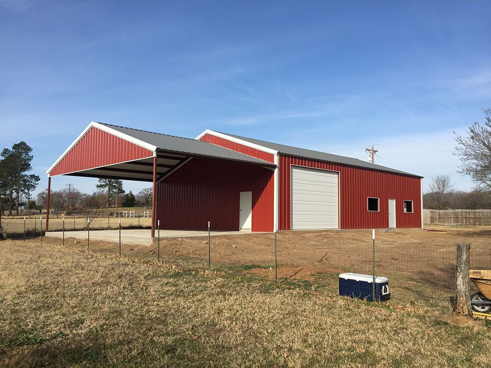 A red barn with a white roof is sitting in the middle of a field.