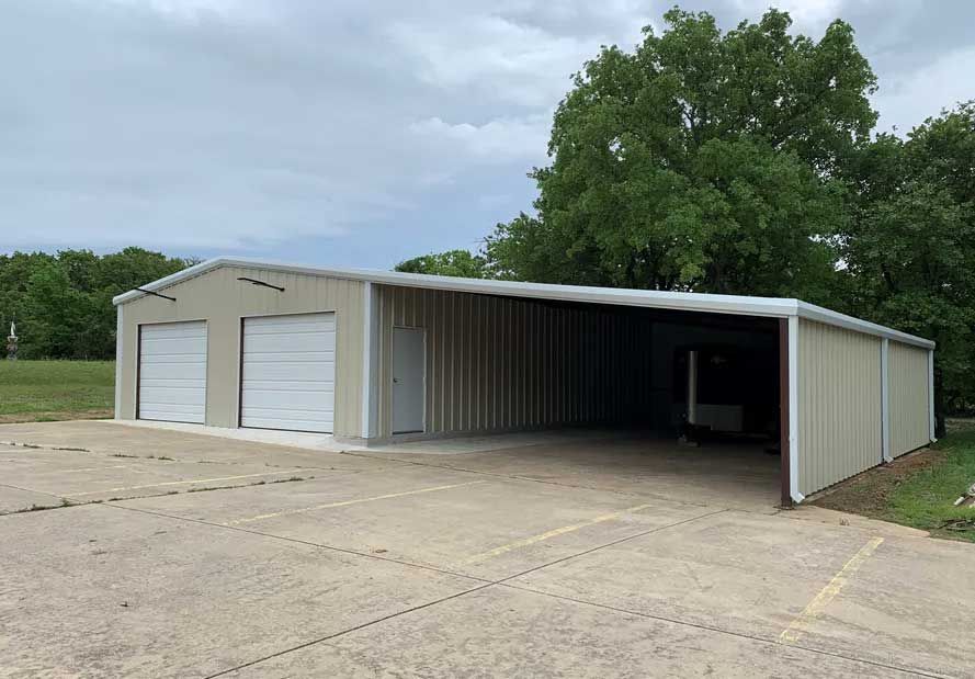 A large metal building with two garage doors and a tree in the background.