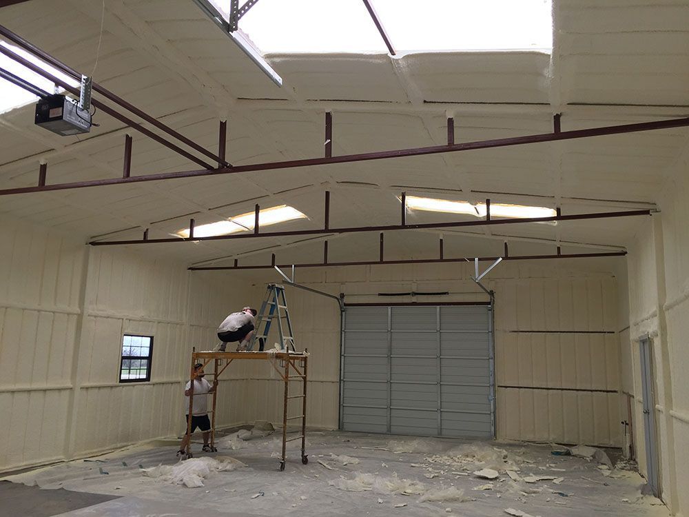 A man is standing on a ladder in a garage.