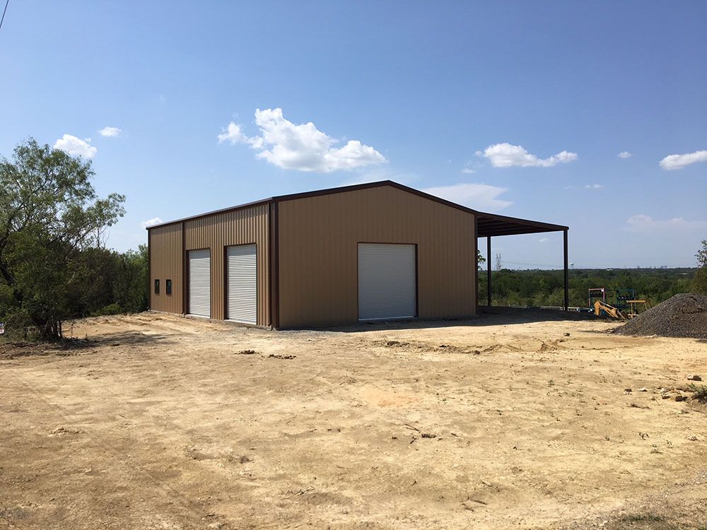 A large metal building is sitting in the middle of a dirt field.