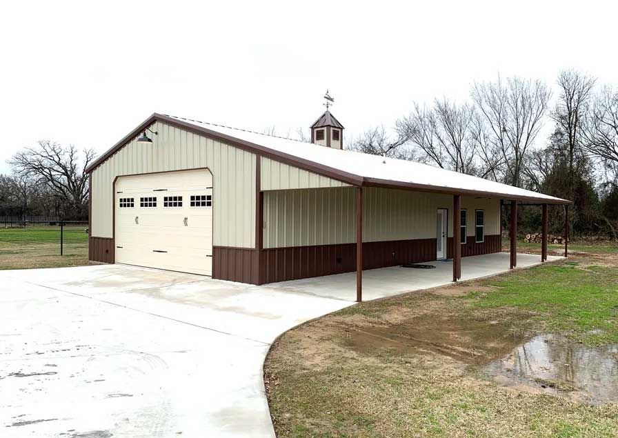 A large metal building with a porch and two garage doors.