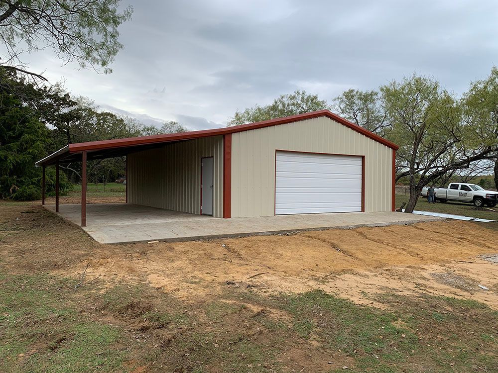 A metal garage with a carport and a truck parked in front of it.