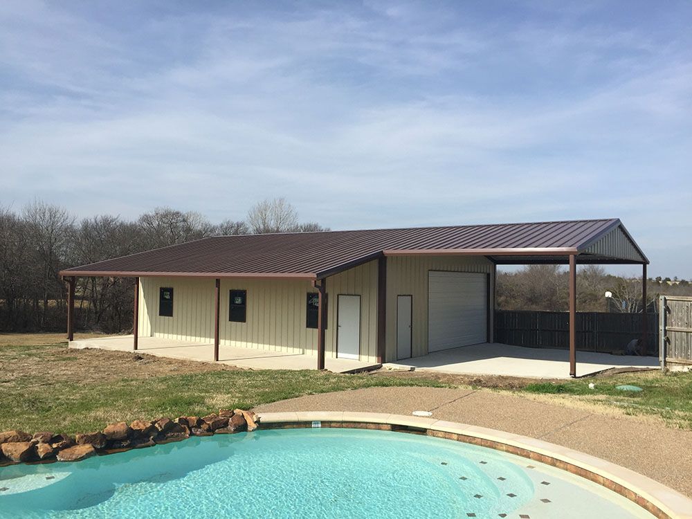 A building with a garage and a pool in front of it.