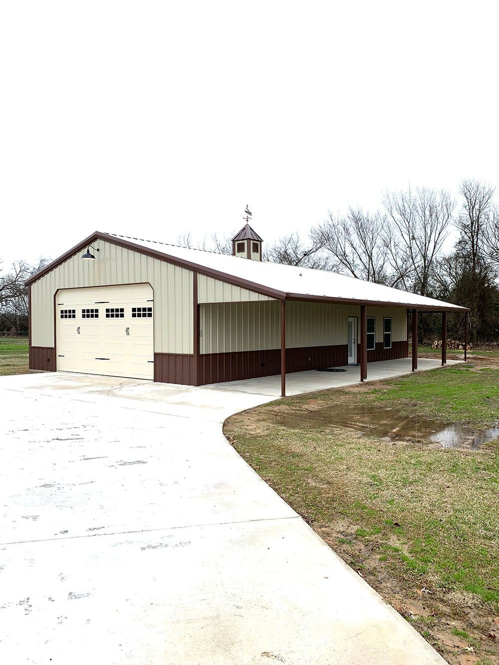 A large metal building with a porch and a driveway.