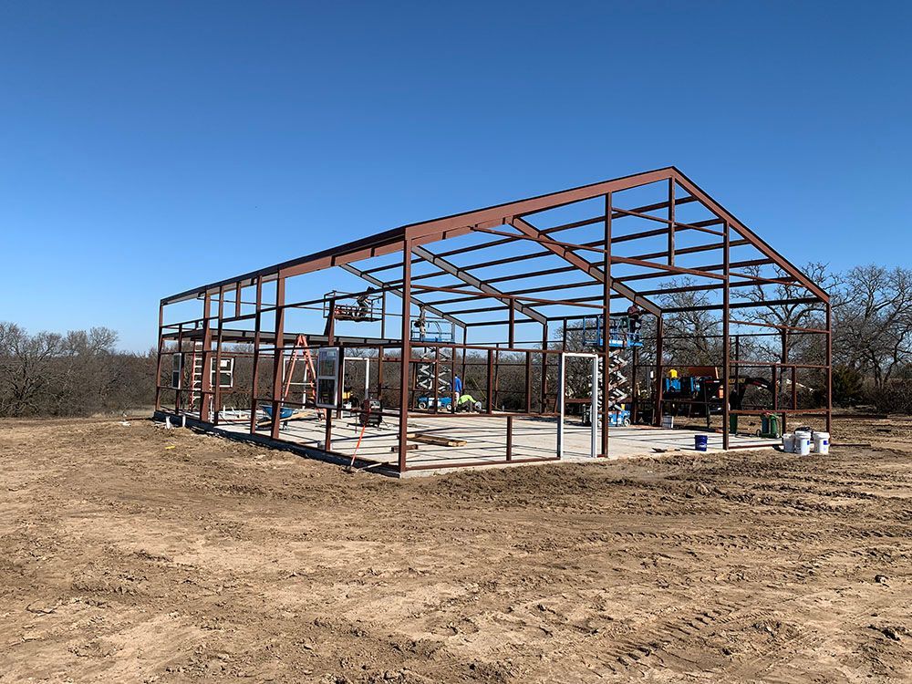 A large metal structure is being built in a dirt field.