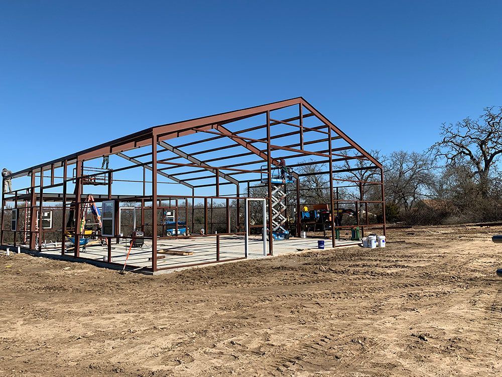 A large metal structure is being built in a dirt field.