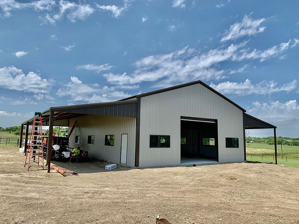 A large metal building is being built in the middle of a dirt field.
