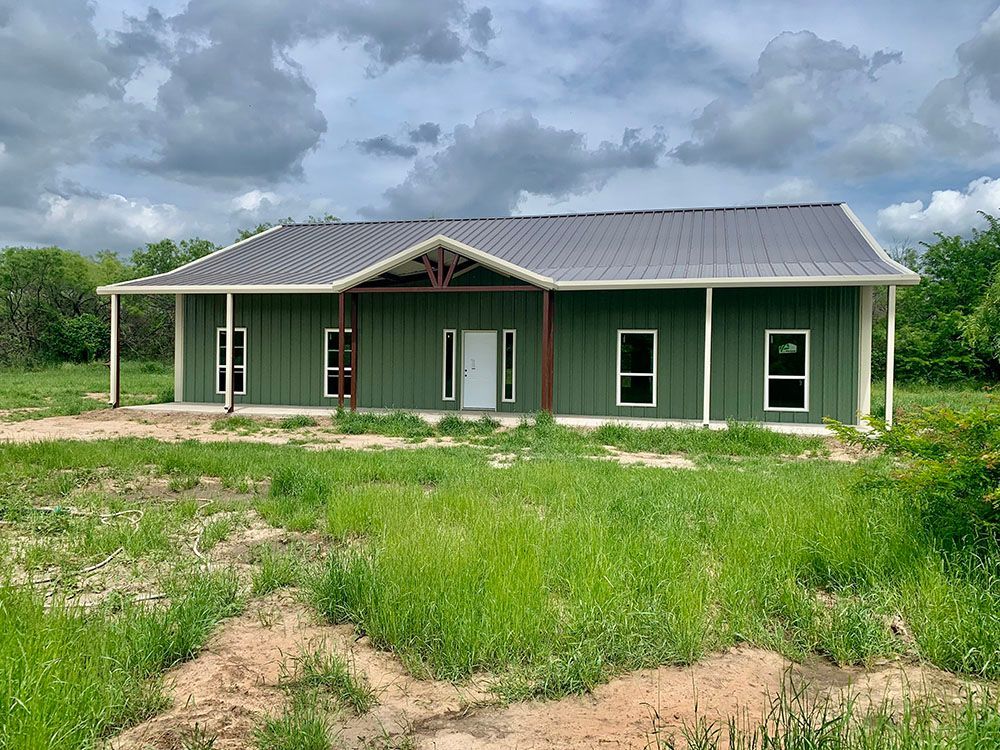 A green house is sitting in the middle of a grassy field.