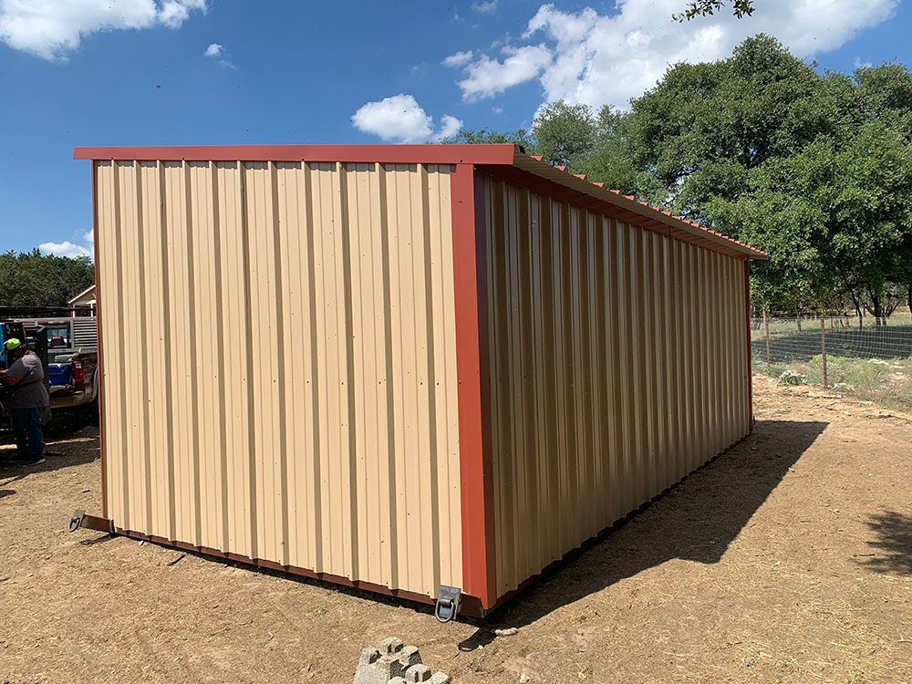 A large metal building is sitting in the middle of a dirt field.