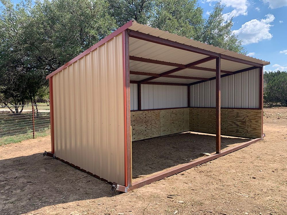 A metal shed is sitting in the middle of a dirt field.