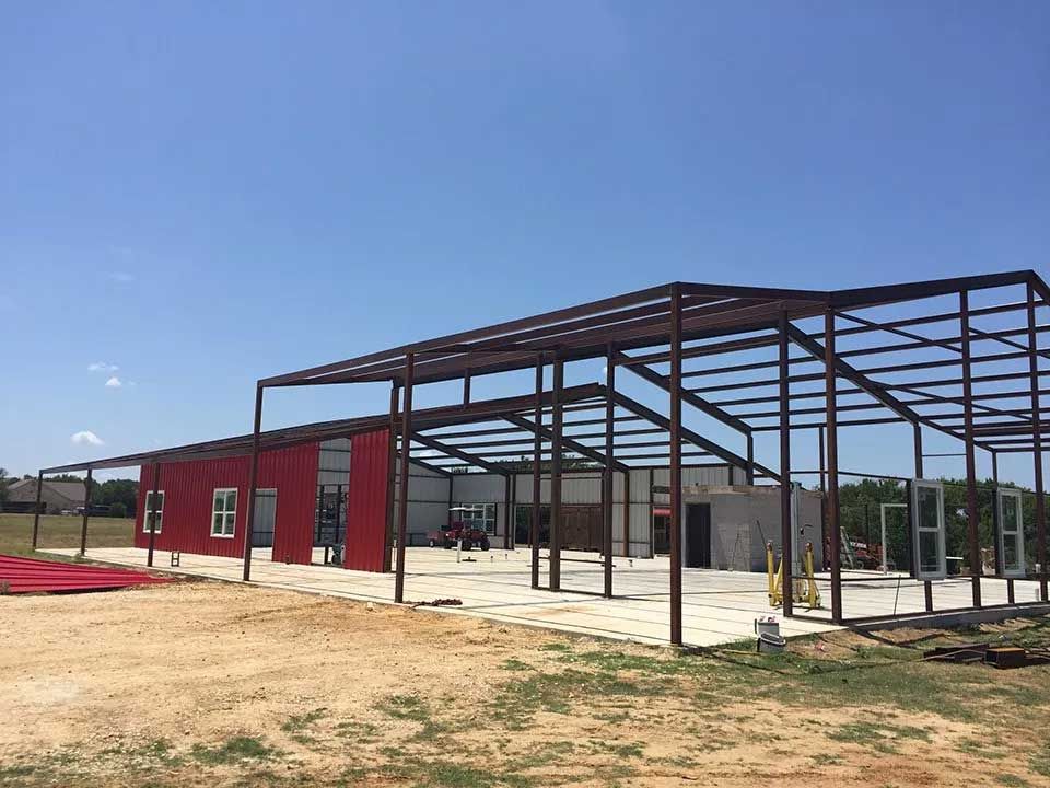 A large metal structure is being built in a field.