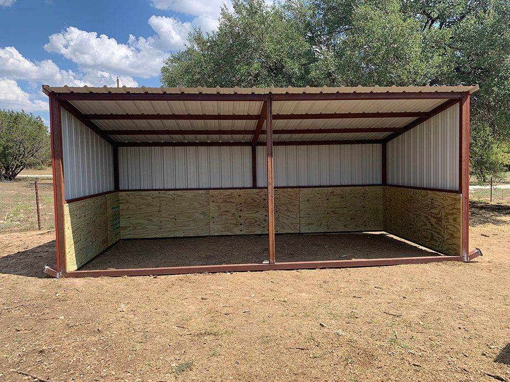A metal shed is sitting in the middle of a dirt field.