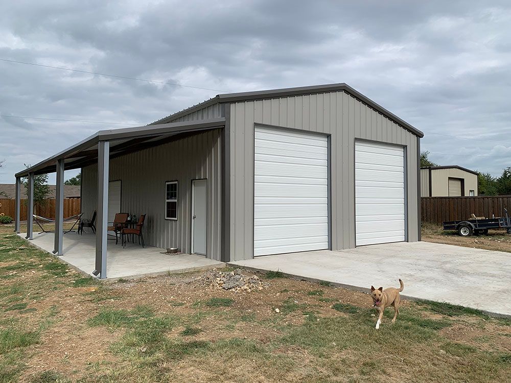 A dog is standing in front of a garage with a porch.