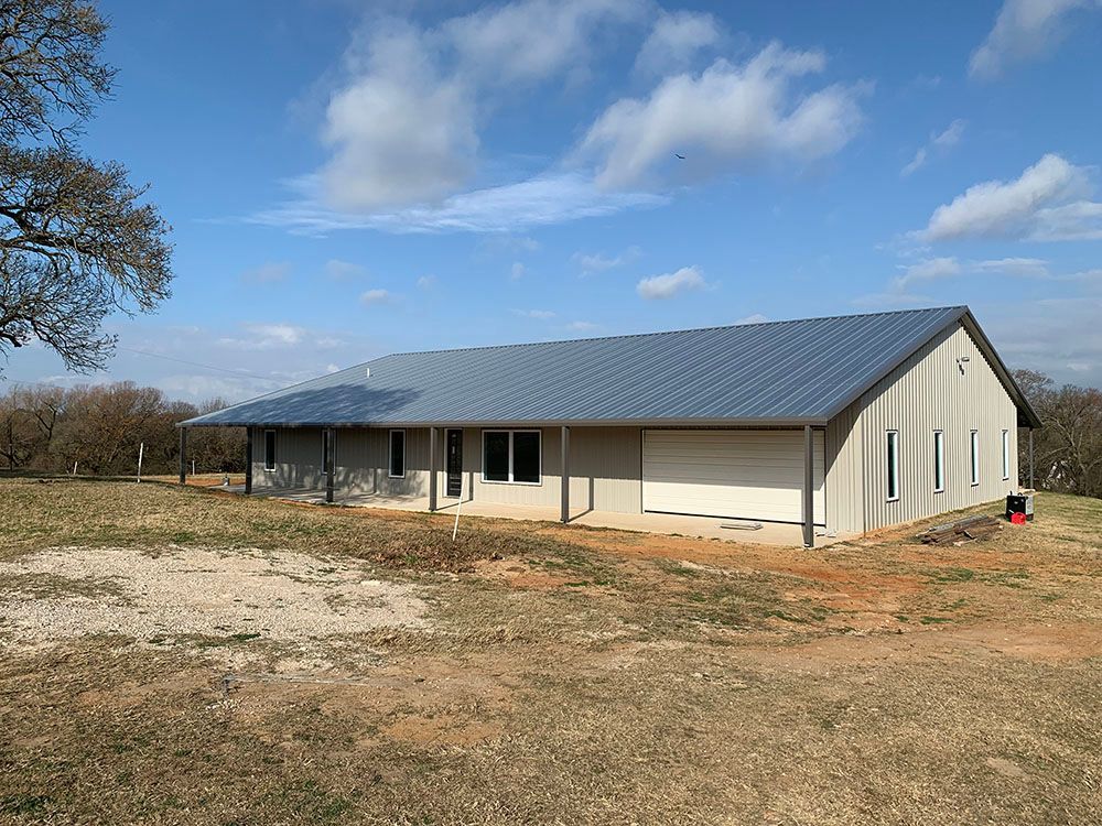 A large metal building is sitting in the middle of a grassy field.