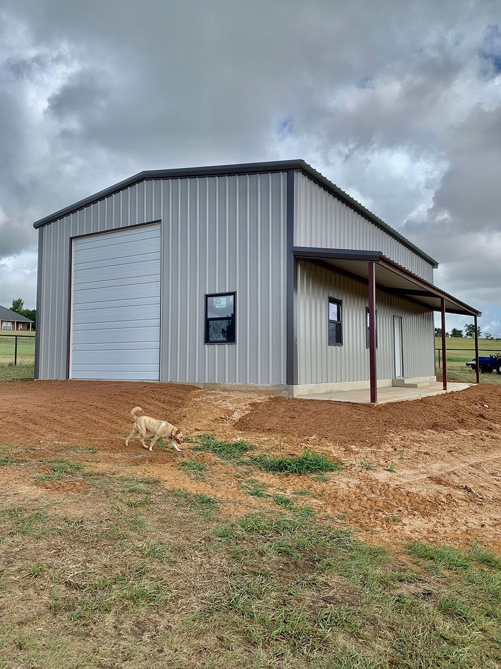 A metal building with a garage door is sitting in the middle of a field.