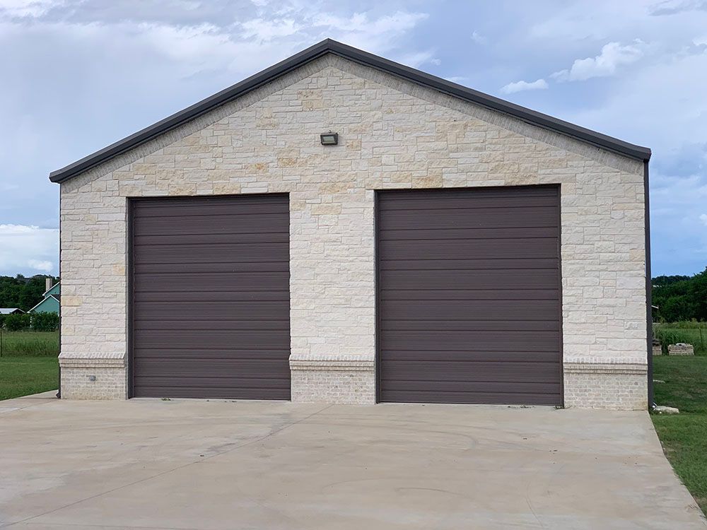 A white brick garage with two brown garage doors and a driveway.