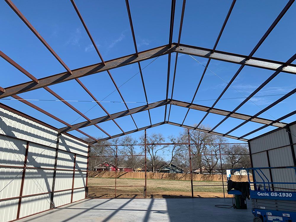 The inside of a metal building under construction with a blue sky in the background.
