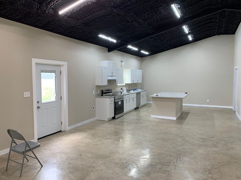 A large empty room with a kitchen and a chair.