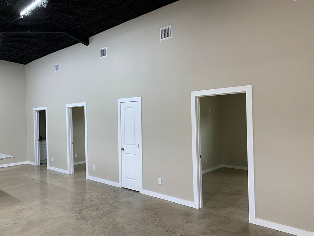 A large empty room with beige walls and white doors.