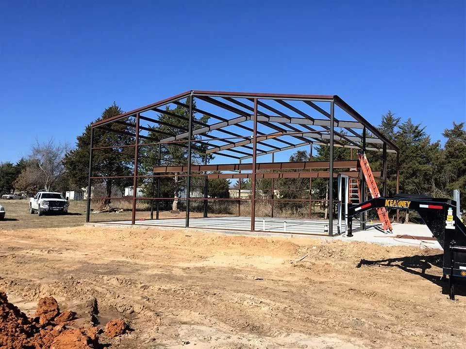 A large metal structure is being built in a dirt field.