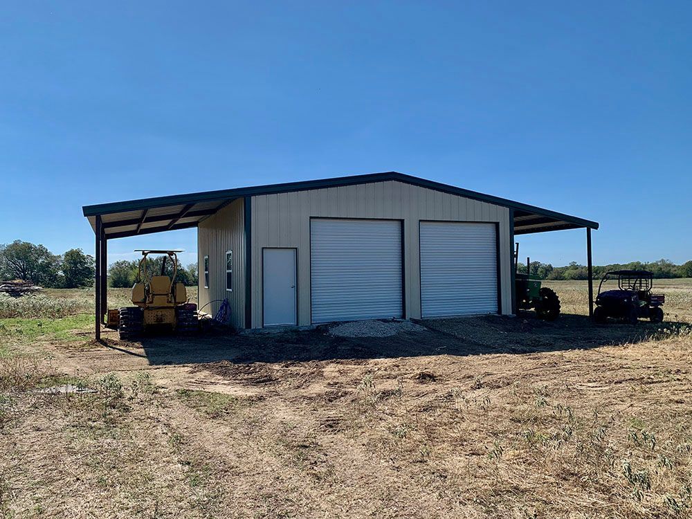 A large metal building with two garage doors and a tractor parked in front of it.