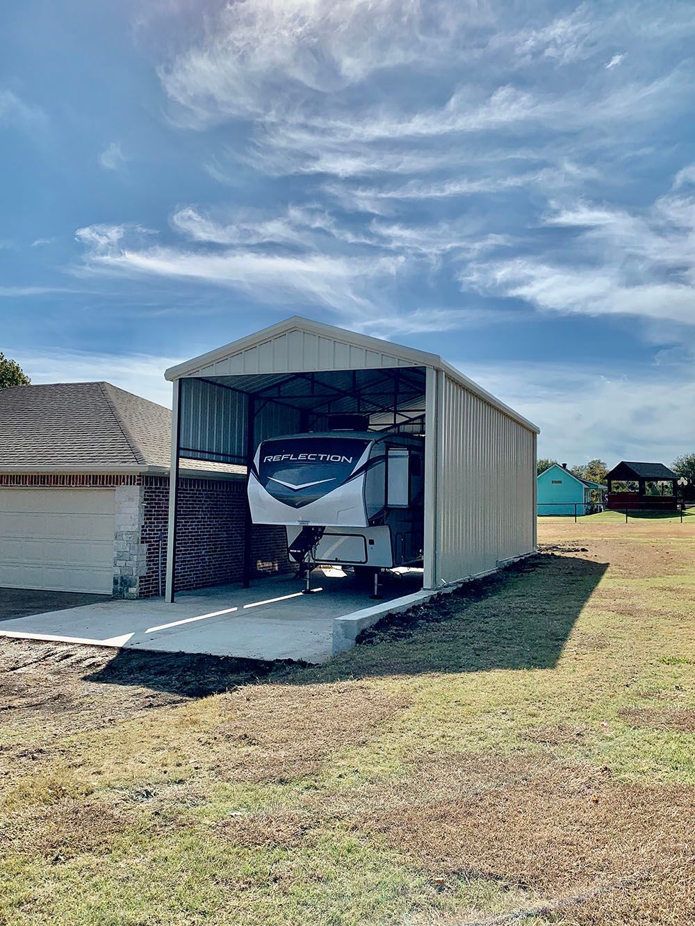 A trailer is parked in a garage next to a house.